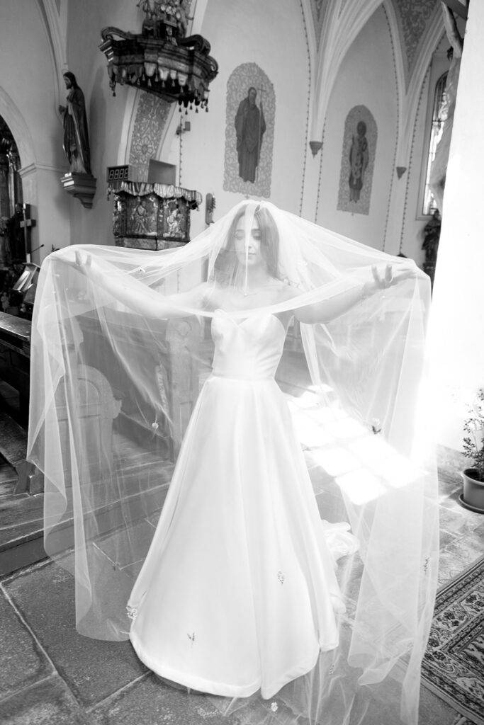 Bride playing with her wedding dress in church after ceremony, black and white artsy photo captured by Lucie Muse