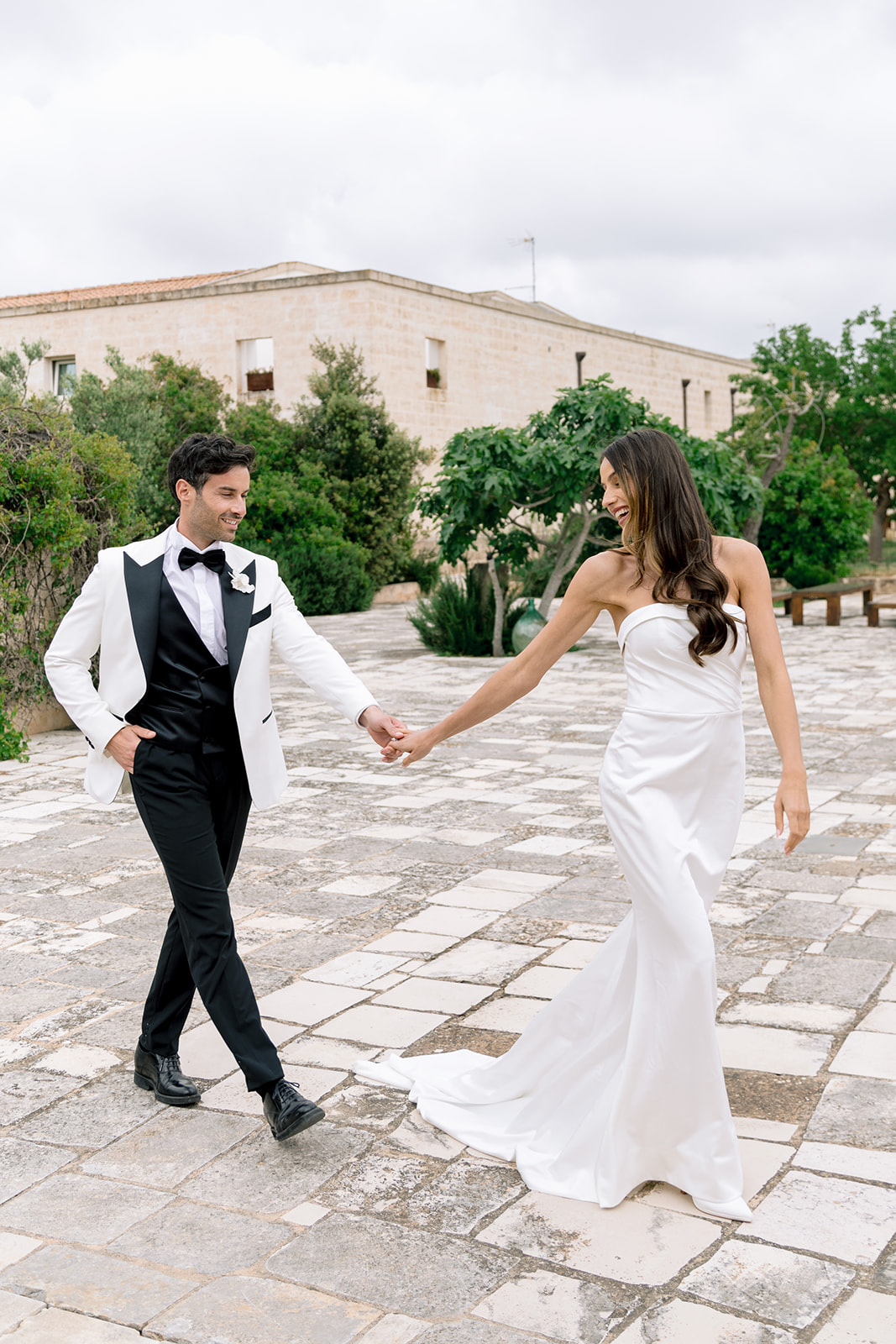 Bride and groom holding hands while walking through historic stone courtyard at Relais Histò.