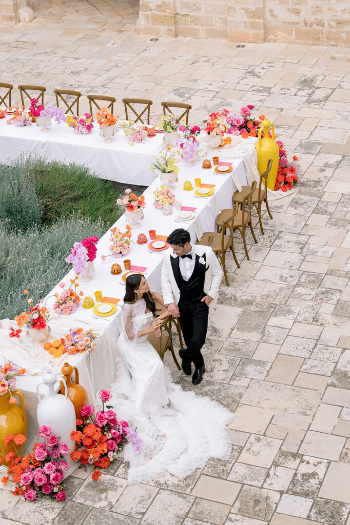 High angle view of a long colorful wedding reception table and groom at Relais Histò in Puglia.