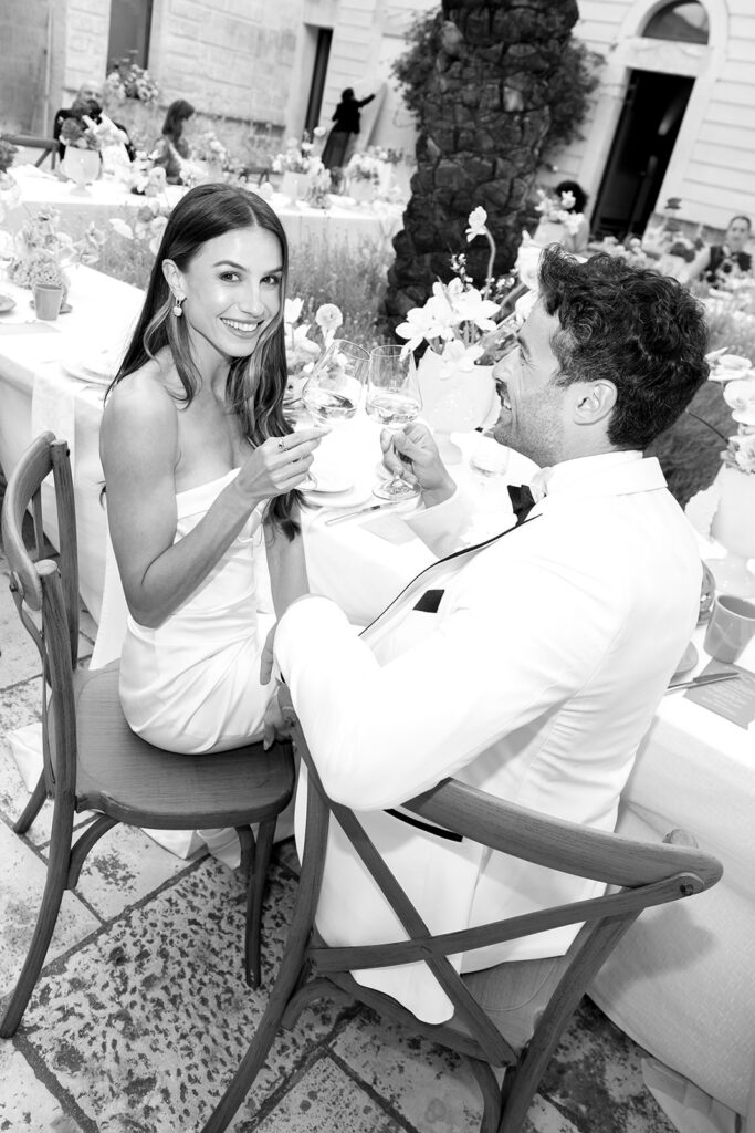 Intimate black and white portrait of bride and groom sharing a moment at their wedding table.