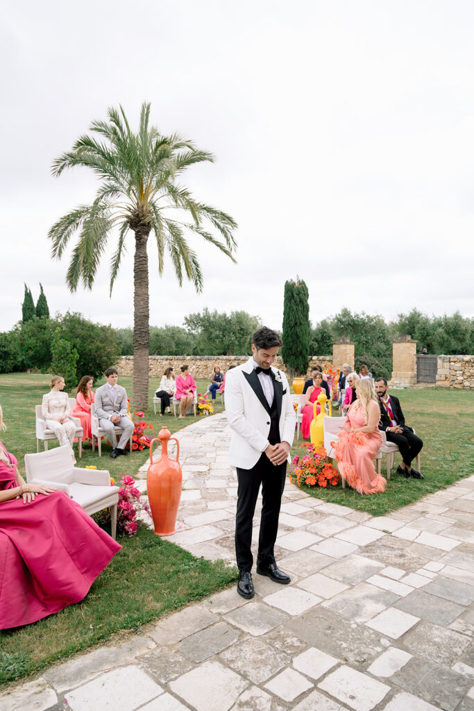 Groom is waiting for his bride in scenic outdoor wedding courtyard with palm tree and historic architecture at Relais Histò.
